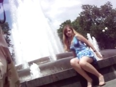 Young girl in a blue dress sitting at the fountain