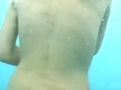 Skinny naked beauty showing her boobs and ass underwater