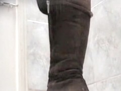 Amateur in high boots sits pissing in public toilet